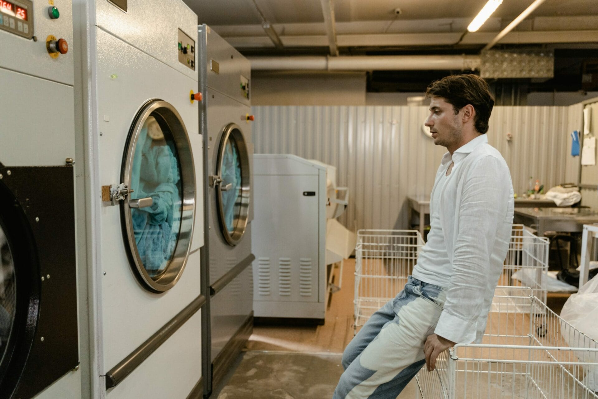 homem esperando suas roupas lavarem na lavadora